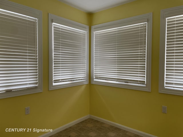unfurnished room with baseboards and carpet flooring