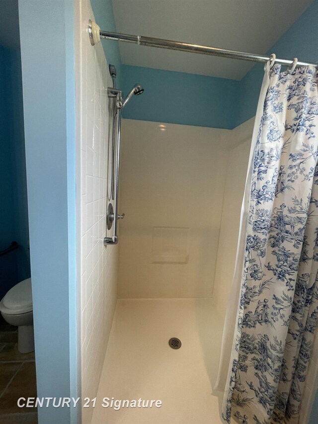 bathroom with a shower with curtain and toilet