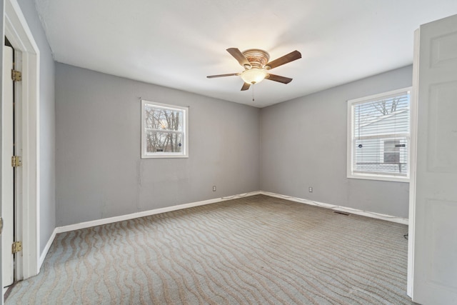 spare room featuring carpet floors, plenty of natural light, and baseboards