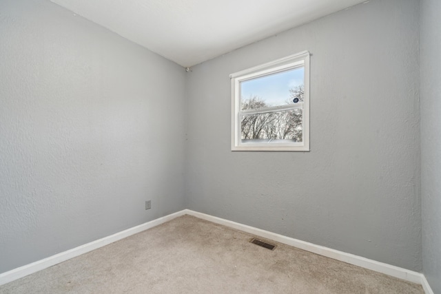 spare room featuring carpet floors, visible vents, and baseboards