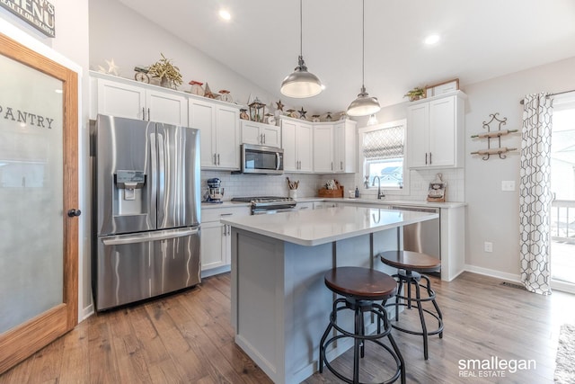 kitchen featuring a breakfast bar area, stainless steel appliances, lofted ceiling, light countertops, and a sink