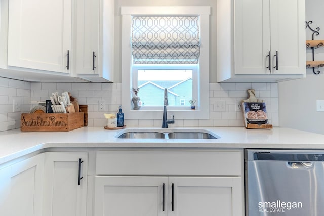 kitchen featuring light countertops, backsplash, white cabinets, a sink, and dishwasher