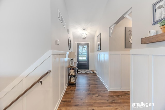 entryway featuring dark wood-style floors, wainscoting, visible vents, and a decorative wall