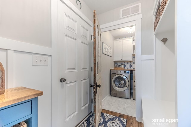 laundry room with washer / clothes dryer, cabinet space, wood finished floors, and visible vents