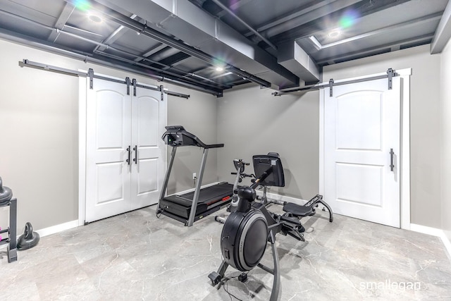 workout room featuring a barn door and baseboards