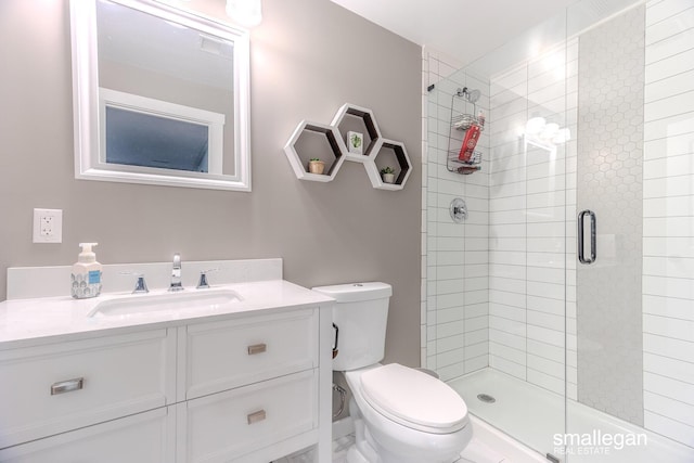 bathroom featuring toilet, a shower stall, and vanity