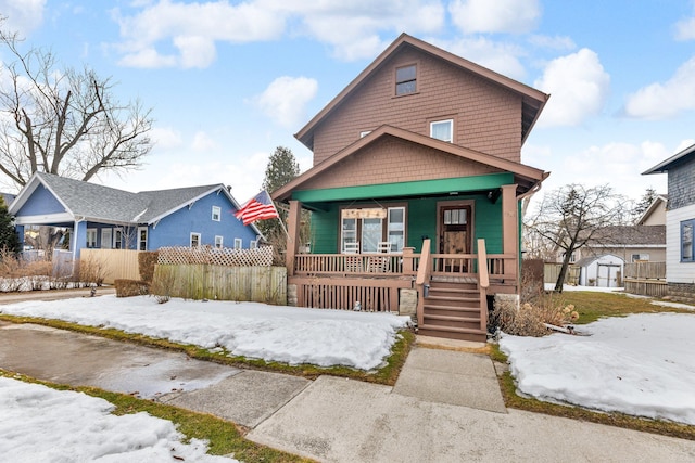 view of front of property with a storage unit, a porch, an outdoor structure, and fence