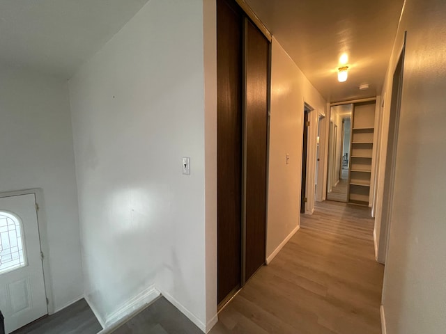 hall with light wood-style flooring and baseboards