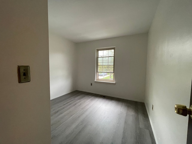 spare room with wood finished floors, visible vents, and baseboards