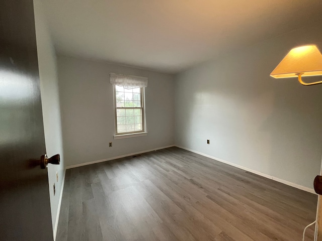 spare room featuring baseboards and wood finished floors