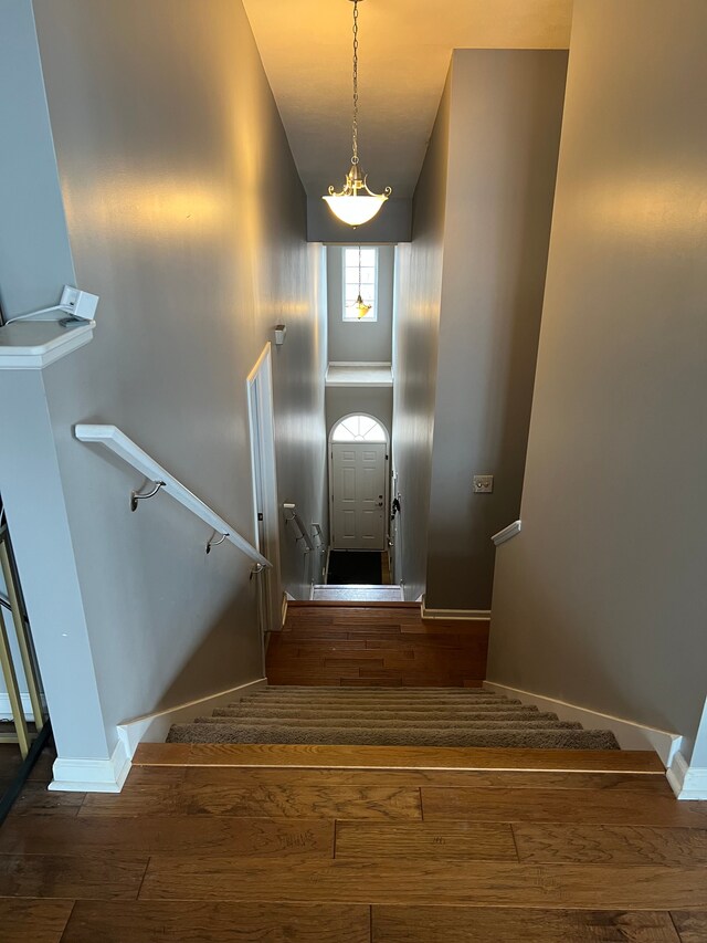 stairs with a high ceiling, wood finished floors, and baseboards