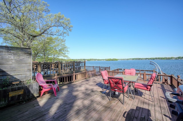 wooden deck with a water view and outdoor dining area