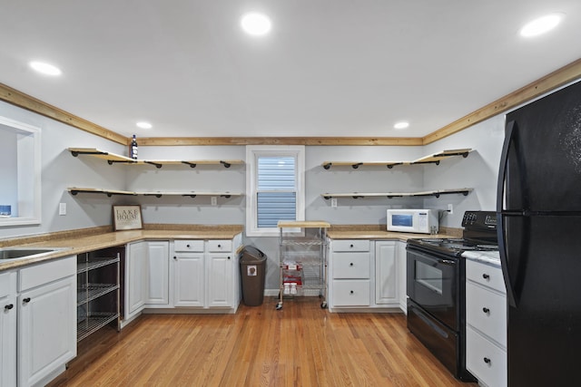 kitchen with light wood-style floors, white cabinets, light countertops, black appliances, and open shelves