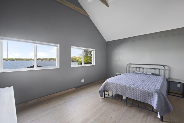 bedroom featuring a water view, beam ceiling, high vaulted ceiling, and wood finished floors