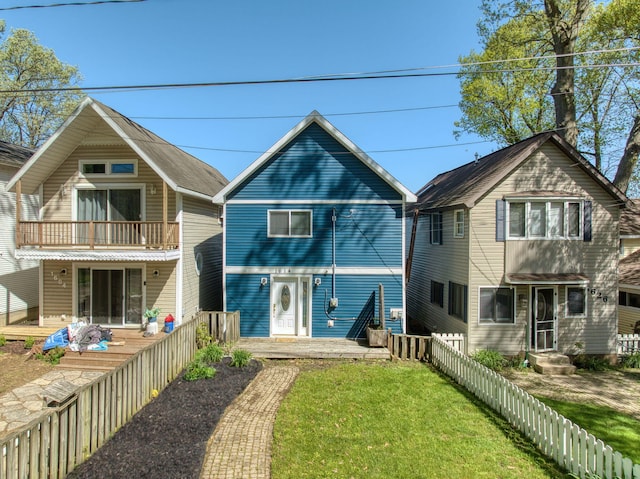 view of front of property featuring a balcony, fence, and a front yard