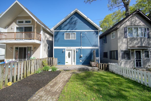 rear view of house with a balcony, fence private yard, and a lawn