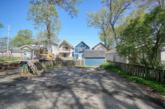 view of front of home with a residential view, an outdoor structure, a storage shed, and fence