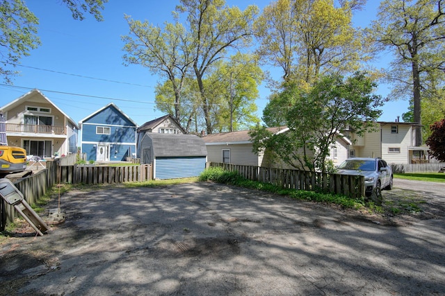 view of front of house featuring an outbuilding, fence, and a storage shed