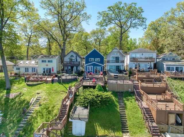 rear view of property featuring a wooden deck, stairs, a residential view, and a yard