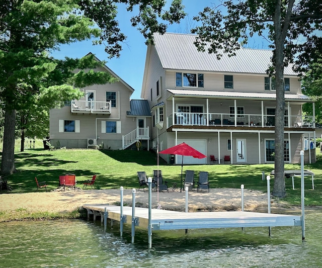 rear view of property featuring metal roof, a water view, and a yard