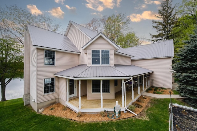 back of property with metal roof, a yard, and a porch