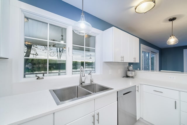 kitchen with decorative light fixtures, light countertops, stainless steel dishwasher, white cabinetry, and a sink