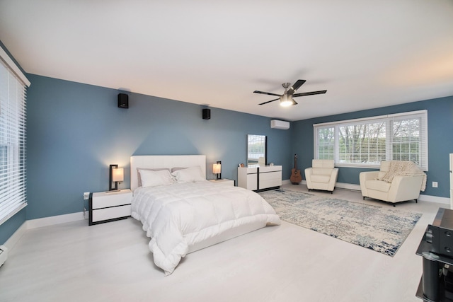 bedroom with a wall mounted AC, a ceiling fan, and baseboards