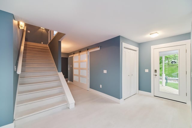 foyer entrance with stairs, a barn door, wood finished floors, and baseboards