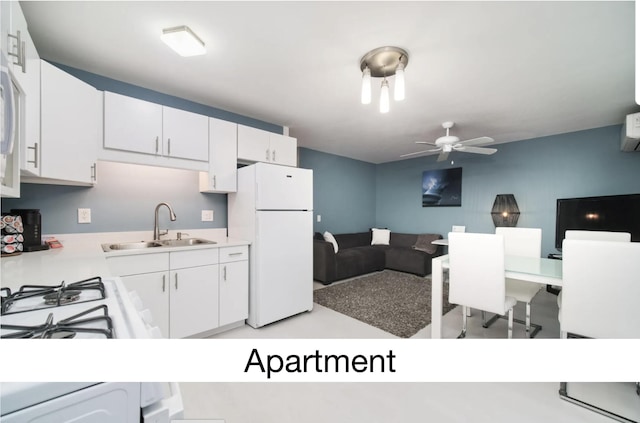 kitchen featuring white cabinets, open floor plan, freestanding refrigerator, light countertops, and a sink