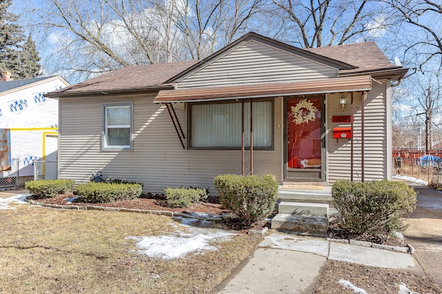 bungalow-style house featuring a shingled roof and fence