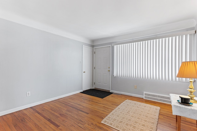 foyer entrance featuring wood finished floors, visible vents, and baseboards