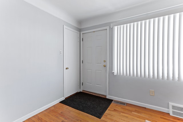 entryway with baseboards, visible vents, and wood finished floors