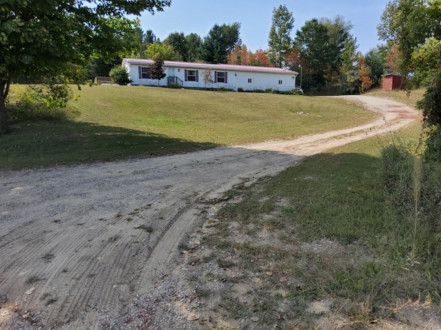 view of front facade with dirt driveway and a front yard