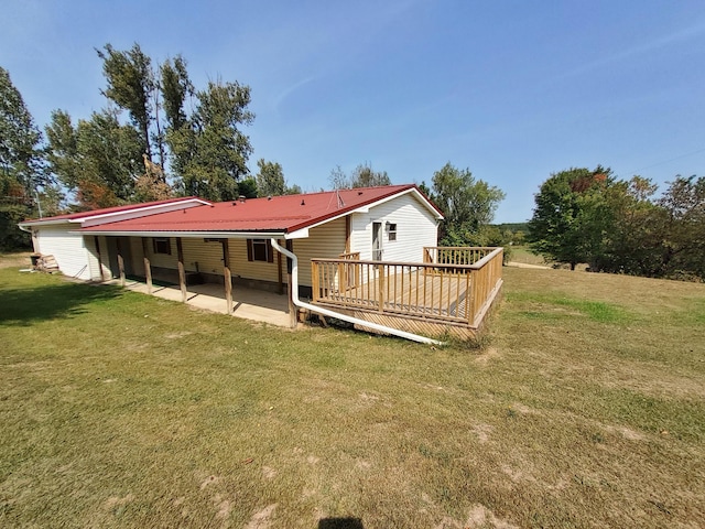 back of property with a patio area, a wooden deck, metal roof, and a yard