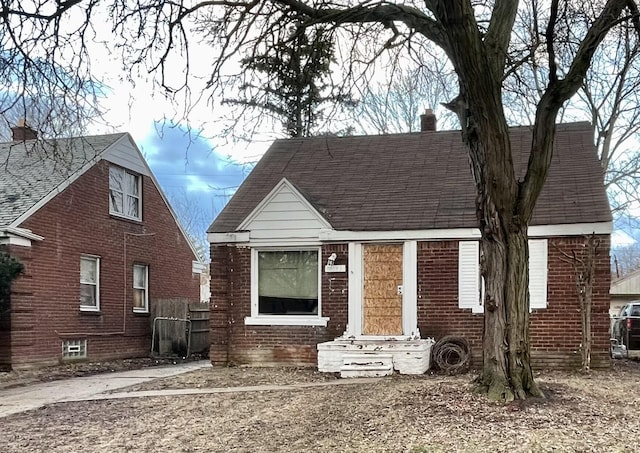 view of front of house with brick siding, a chimney, and a shingled roof