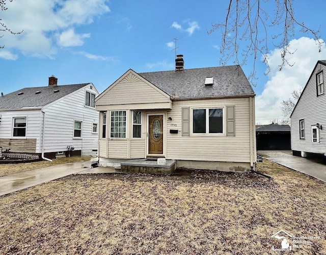 view of front of property featuring concrete driveway and roof with shingles