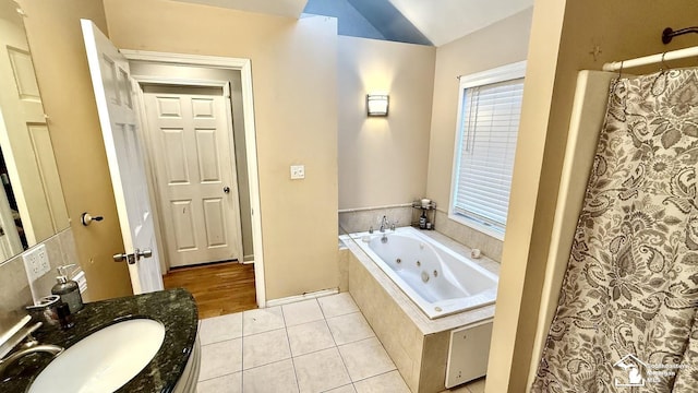 full bathroom with a shower with shower curtain, a tub with jets, tile patterned flooring, vaulted ceiling, and vanity