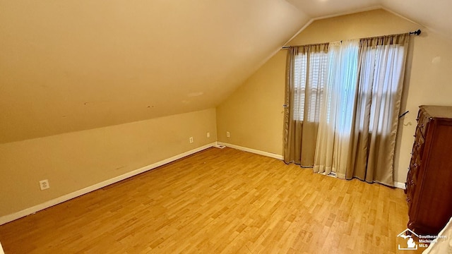 additional living space with light wood-style floors, baseboards, and vaulted ceiling