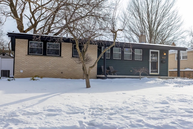 single story home featuring a chimney, cooling unit, and brick siding