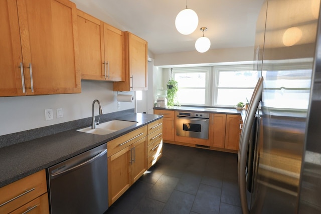 kitchen featuring dark countertops, dark tile patterned floors, stainless steel appliances, and a sink