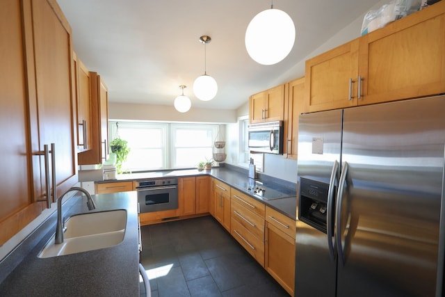 kitchen with stainless steel appliances, dark tile patterned flooring, a sink, dark countertops, and pendant lighting