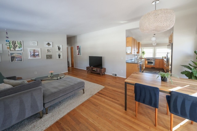 living room featuring light wood-type flooring, visible vents, and baseboards