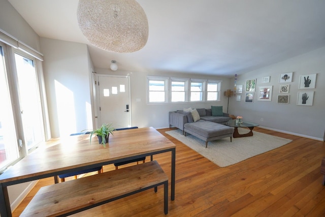 living area featuring lofted ceiling, light wood-style flooring, and baseboards