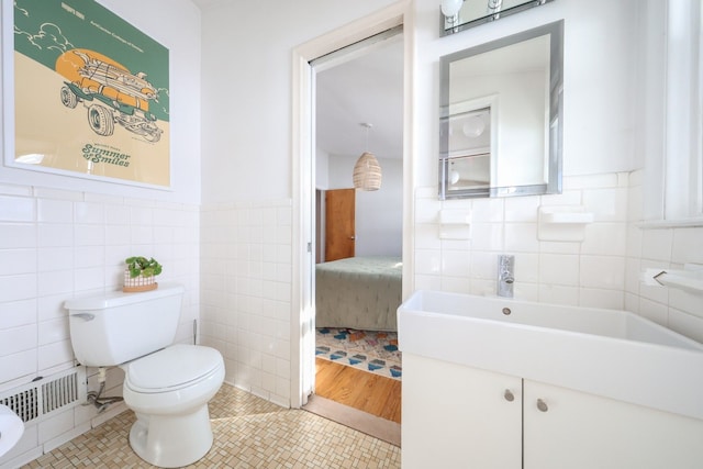 bathroom featuring tile walls, visible vents, toilet, vanity, and tile patterned flooring