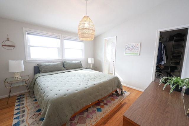 bedroom with lofted ceiling, baseboards, a spacious closet, and light wood finished floors