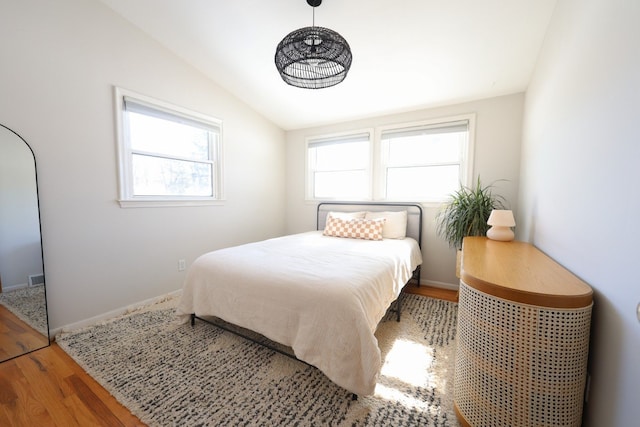 bedroom with lofted ceiling, multiple windows, wood finished floors, and baseboards