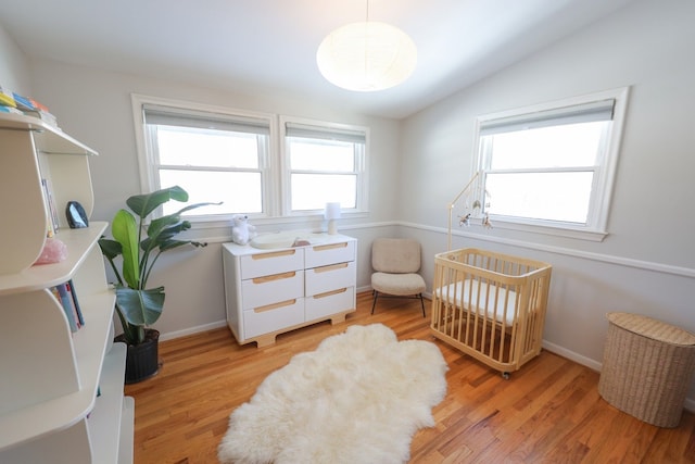 bedroom with vaulted ceiling, light wood finished floors, and baseboards