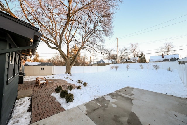 yard covered in snow featuring an outbuilding, a storage unit, a patio area, and a fenced backyard