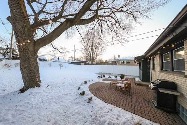 snowy yard with a fenced backyard and a patio