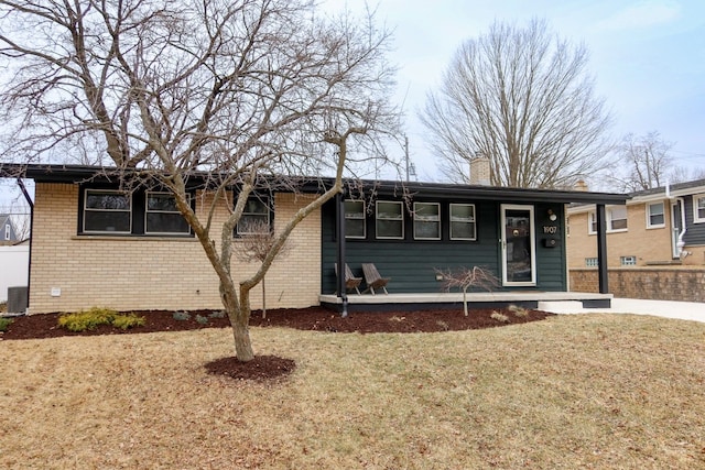 ranch-style home featuring brick siding, a chimney, and a front lawn